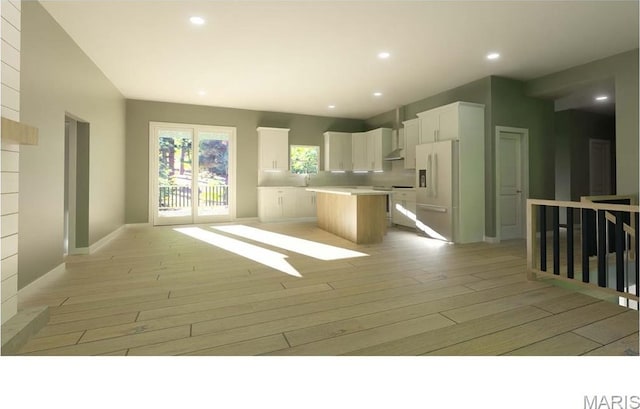 kitchen with white fridge with ice dispenser, a center island, light wood finished floors, open floor plan, and white cabinets