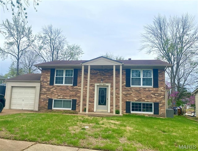 bi-level home with an attached garage, a front lawn, brick siding, and central air condition unit