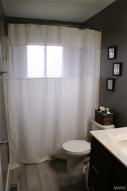 bathroom featuring vanity, toilet, wood finished floors, and a shower with curtain