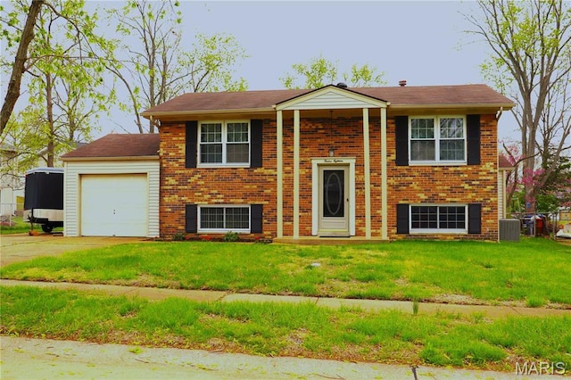 split foyer home featuring a garage, brick siding, a front yard, and concrete driveway