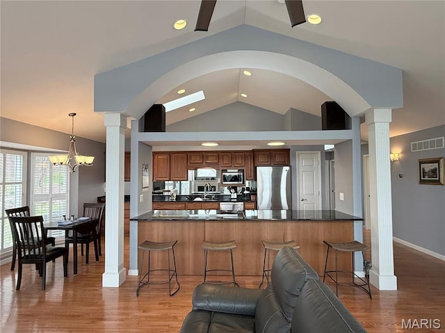 kitchen featuring appliances with stainless steel finishes, vaulted ceiling, decorative columns, dark countertops, and recessed lighting