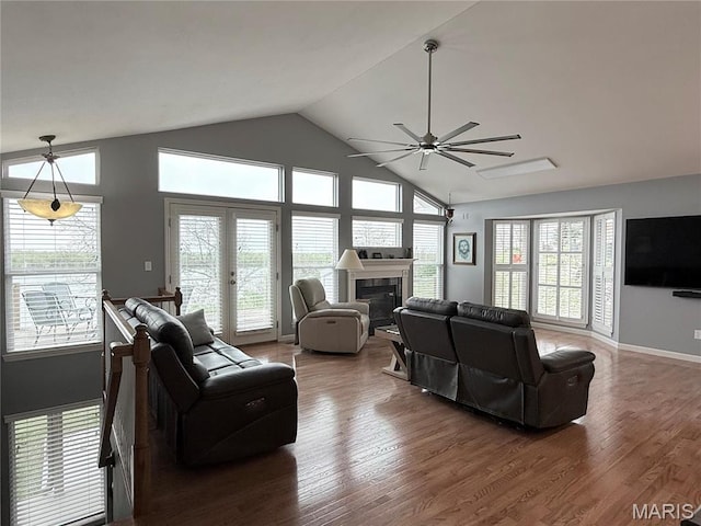 living room featuring ceiling fan, wood finished floors, a glass covered fireplace, high vaulted ceiling, and baseboards