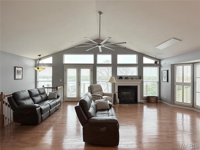 living area featuring wood finished floors, healthy amount of natural light, ceiling fan, and high vaulted ceiling