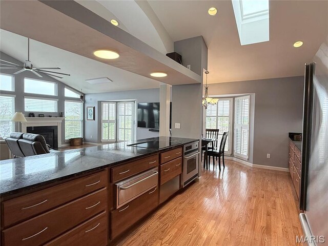 kitchen featuring stainless steel appliances, a warming drawer, lofted ceiling, ceiling fan, and plenty of natural light