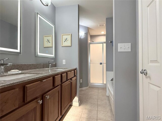 bathroom with tile patterned flooring, a shower stall, a garden tub, double vanity, and baseboards