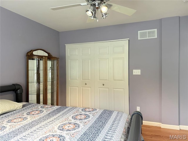 bedroom featuring a closet, wood finished floors, a ceiling fan, and baseboards