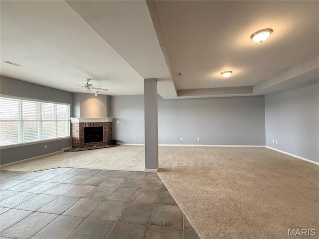 unfurnished living room with ceiling fan, dark carpet, baseboards, and a brick fireplace