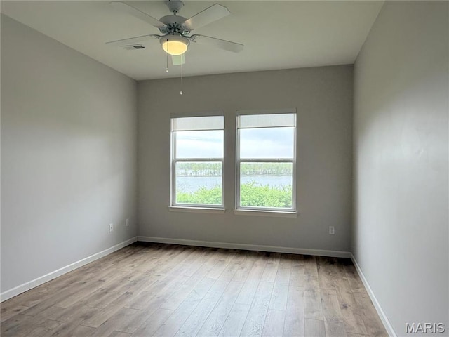 empty room featuring wood finished floors, baseboards, and ceiling fan