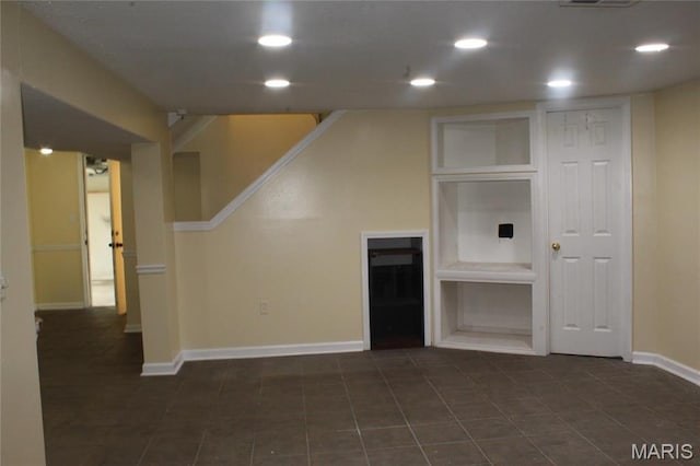 unfurnished living room with baseboards, recessed lighting, and dark tile patterned flooring