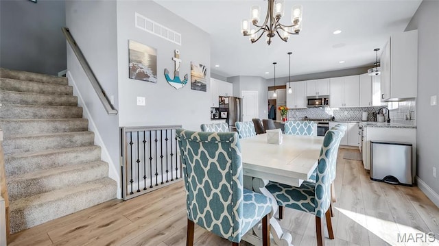 dining area featuring a chandelier, light wood-style flooring, stairway, and recessed lighting