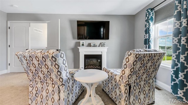 sitting room with baseboards, carpet, and a glass covered fireplace