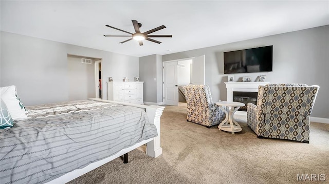 bedroom with carpet, baseboards, a glass covered fireplace, and ceiling fan