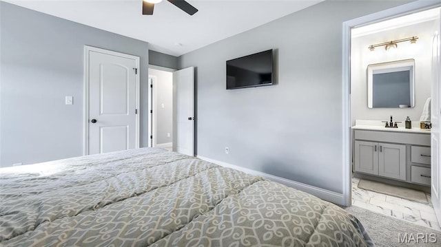 carpeted bedroom with baseboards, a sink, ensuite bathroom, and ceiling fan