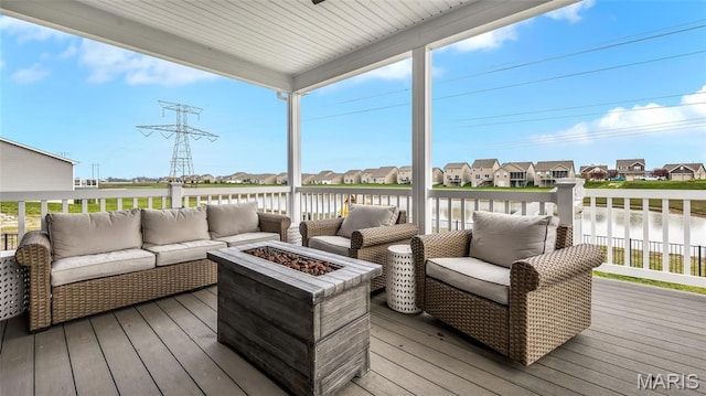 deck featuring an outdoor living space with a fire pit, a residential view, and a water view