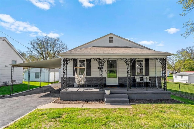view of front facade with covered porch, asphalt driveway, stone siding, and a carport