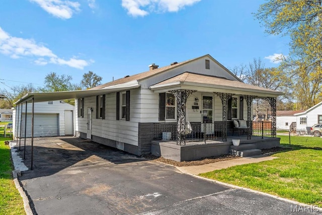 view of front facade featuring covered porch, an outbuilding, asphalt driveway, and a garage