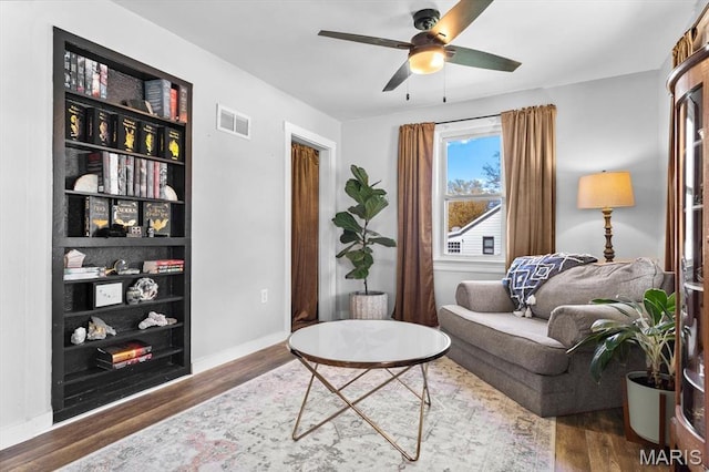 living area featuring wood finished floors, ceiling fan, and baseboards