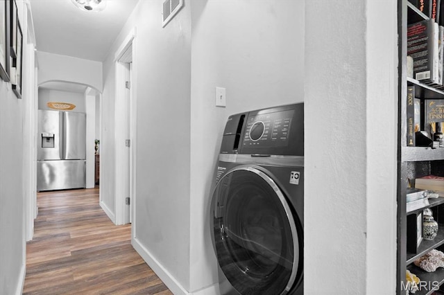 washroom with washer / clothes dryer, arched walkways, wood finished floors, and baseboards