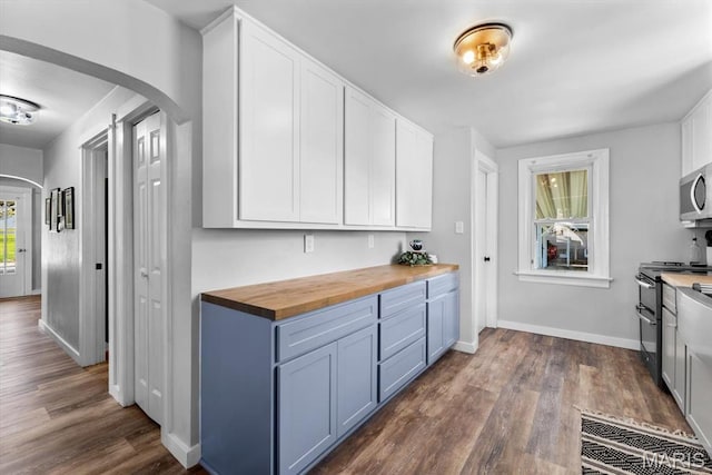 kitchen featuring arched walkways, butcher block countertops, range with two ovens, dark wood-style floors, and white cabinetry