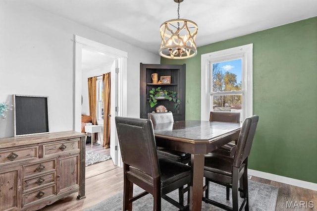 dining area with a chandelier, light wood-style floors, and baseboards