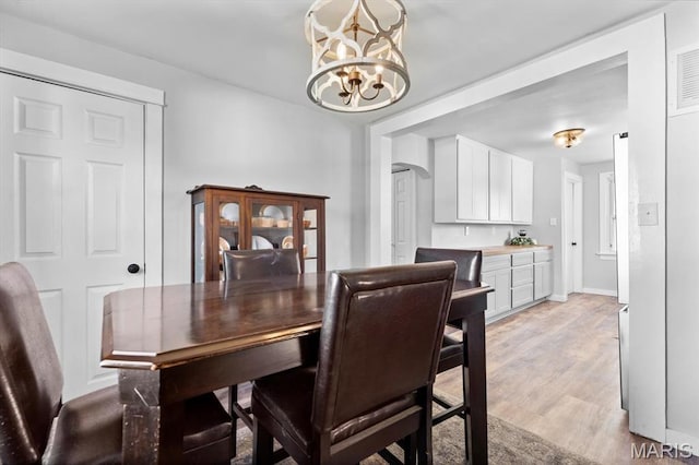 dining space featuring a chandelier, arched walkways, and light wood finished floors