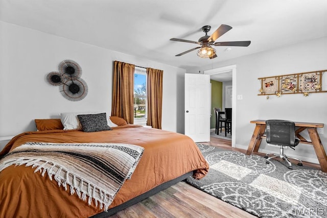 bedroom featuring wood finished floors, baseboards, a desk, and a ceiling fan