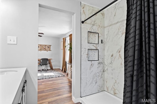 bathroom with a stall shower, vanity, wood finished floors, and a ceiling fan