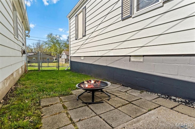 view of side of property with a fire pit, crawl space, a patio, and a gate