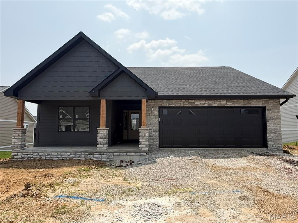 2253 Heywood Mdws, Cape Girardeau, MO 63701 - view of front facade featuring a porch, a garage, dirt driveway, stone siding, and a shingled roof