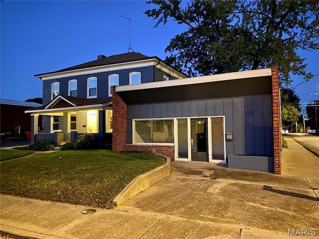 view of front facade featuring a front lawn, a chimney, and board and batten siding