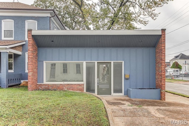 view of front of house with board and batten siding, a front lawn, and brick siding