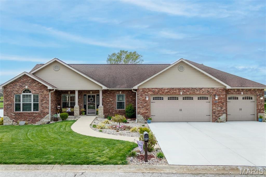 view of front facade with a garage, a front yard, concrete driveway, and brick siding