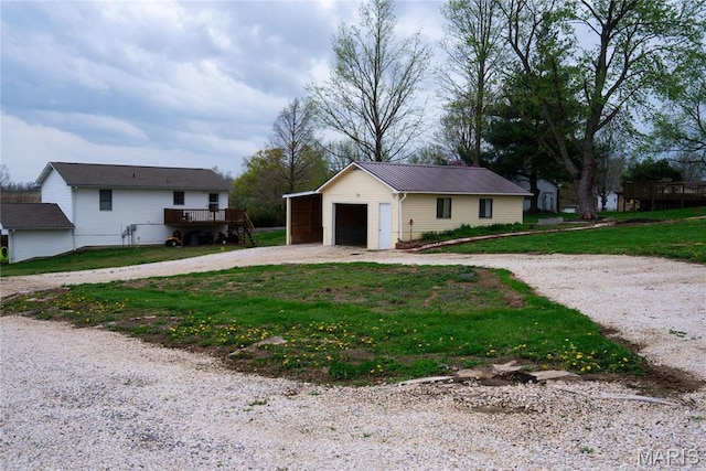 single story home with an outbuilding, gravel driveway, a detached garage, a front yard, and metal roof