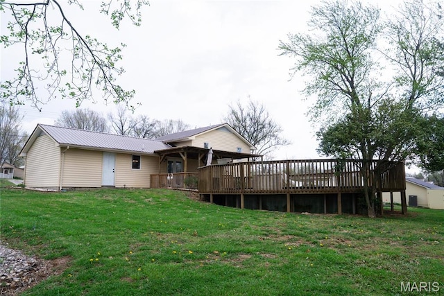 back of house featuring a deck, metal roof, and a lawn