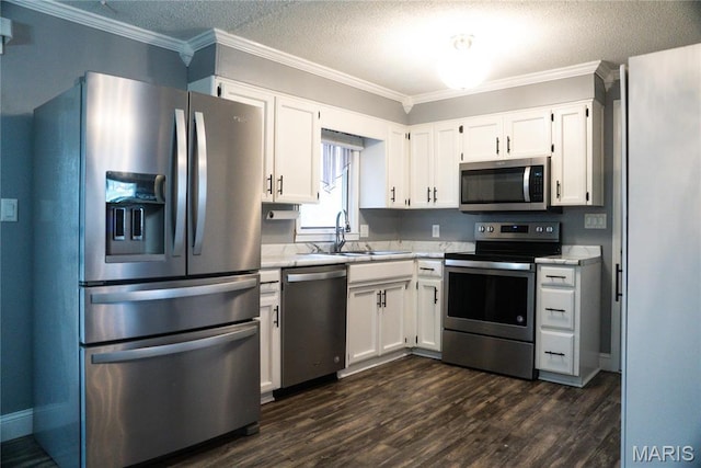 kitchen featuring appliances with stainless steel finishes, a sink, light countertops, white cabinetry, and a textured ceiling