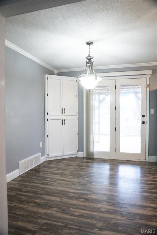 unfurnished dining area with baseboards, ornamental molding, dark wood-style floors, and a textured ceiling
