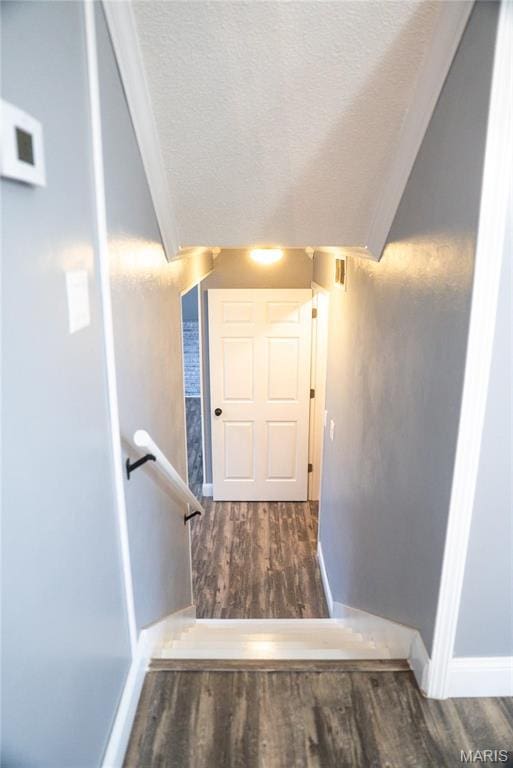 stairs featuring wood finished floors, a textured ceiling, and baseboards
