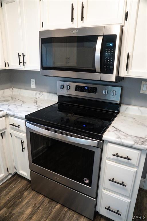 kitchen featuring stainless steel appliances, white cabinets, dark wood-style floors, and light stone counters