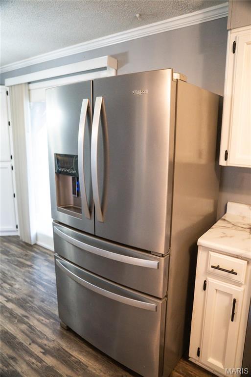 kitchen with stainless steel refrigerator with ice dispenser, a textured ceiling, dark wood-type flooring, white cabinets, and crown molding