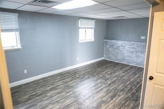 basement featuring a paneled ceiling, dark wood-style flooring, and baseboards