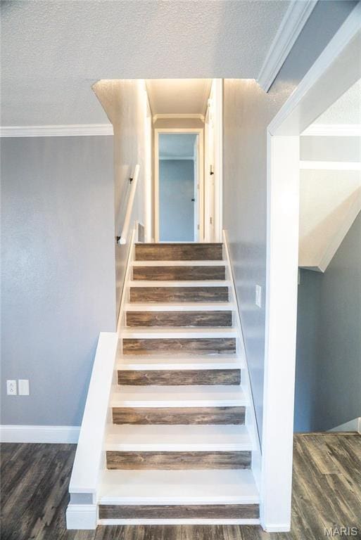 staircase with wood finished floors, ornamental molding, baseboards, and a textured ceiling