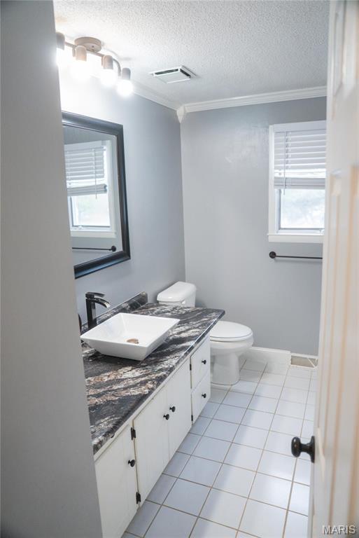 bathroom featuring crown molding, toilet, vanity, a textured ceiling, and tile patterned floors