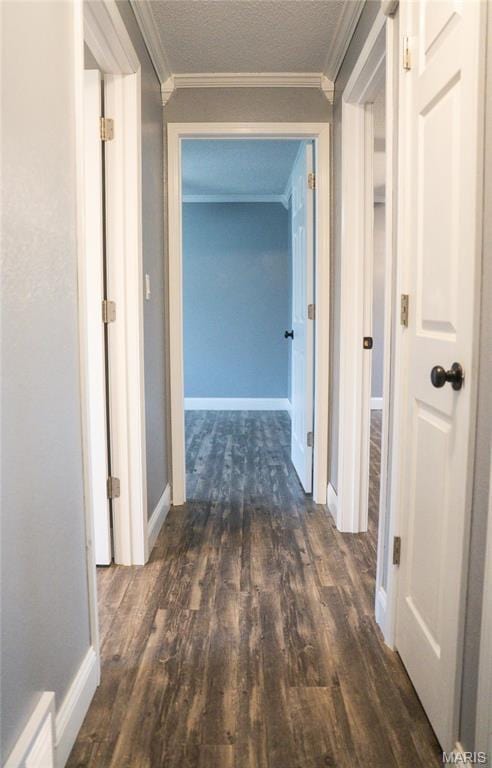 corridor featuring wood finished floors, crown molding, and baseboards