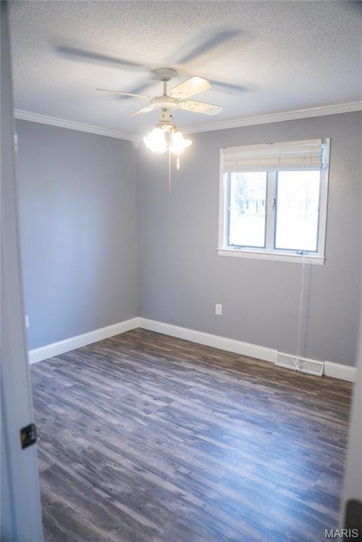 unfurnished room featuring crown molding, a textured ceiling, a ceiling fan, dark wood-style floors, and baseboards