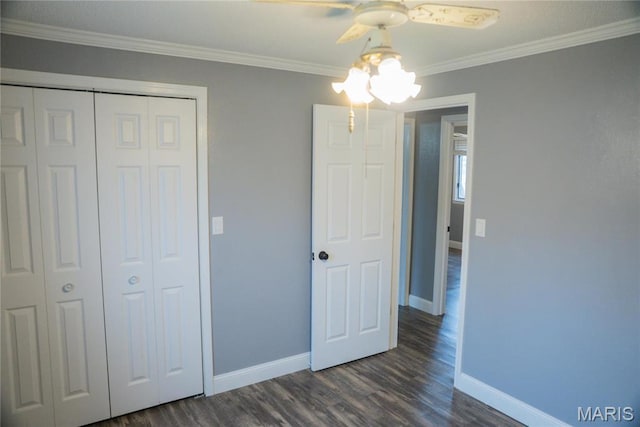 unfurnished bedroom with baseboards, a closet, crown molding, dark wood finished floors, and a ceiling fan