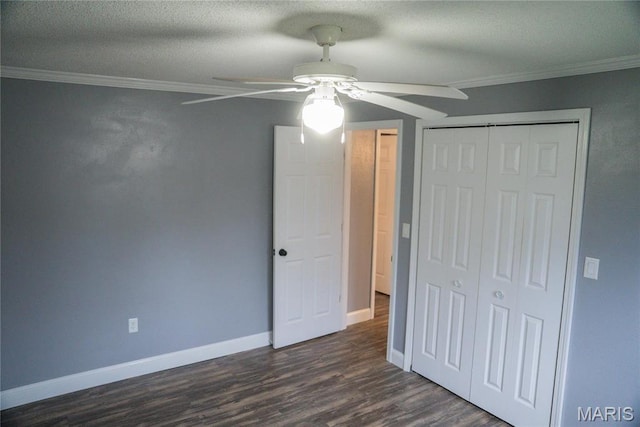 unfurnished bedroom with ornamental molding, a closet, dark wood-type flooring, baseboards, and ceiling fan
