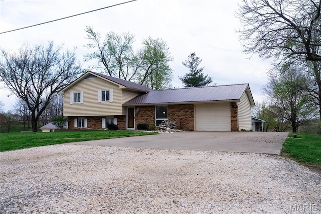 split level home with driveway, an attached garage, brick siding, metal roof, and a front yard