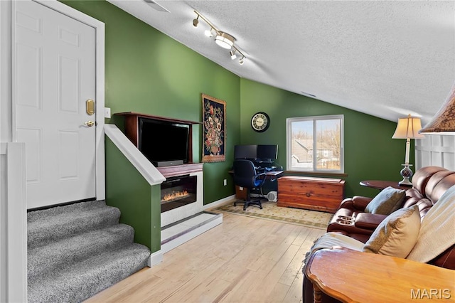 1009 Hemingway Ln Unit H, Weldon Spring, MO 63304 - living area with a textured ceiling, a glass covered fireplace, lofted ceiling, wood finished floors, and baseboards