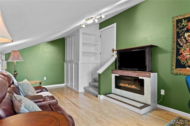 1009 Hemingway Ln Unit H, Weldon Spring, MO 63304 - living room featuring a glass covered fireplace, a textured ceiling, wood finished floors, stairs, and baseboards