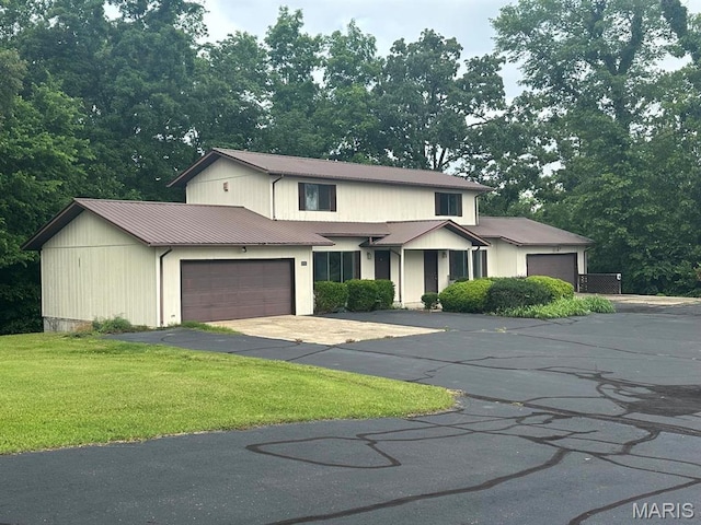 view of front of house with a front yard, an attached garage, and asphalt driveway